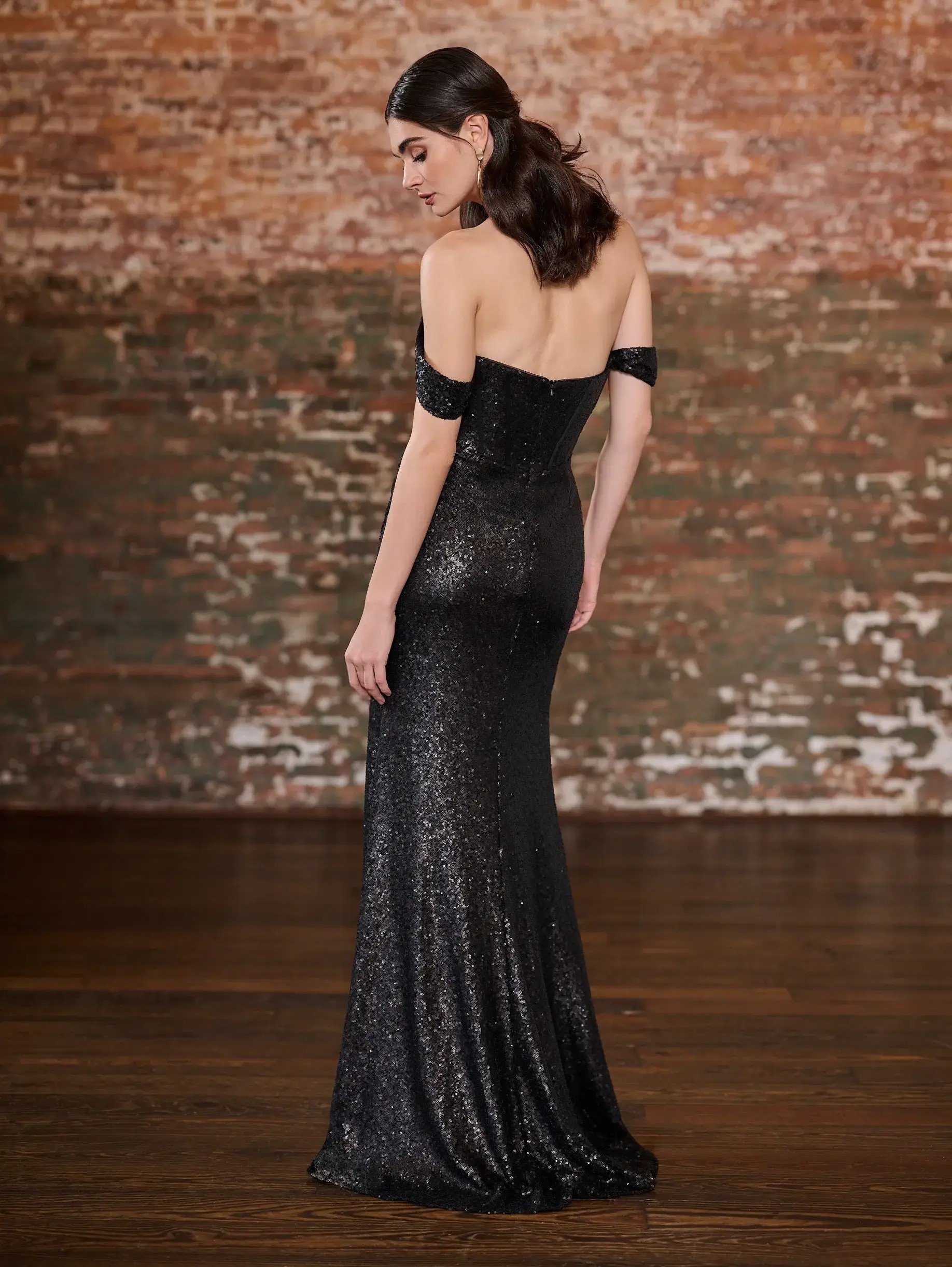 Model is wearing a sequin bridesmaid dress with an off the shoulder neckline and corset style bodice 
