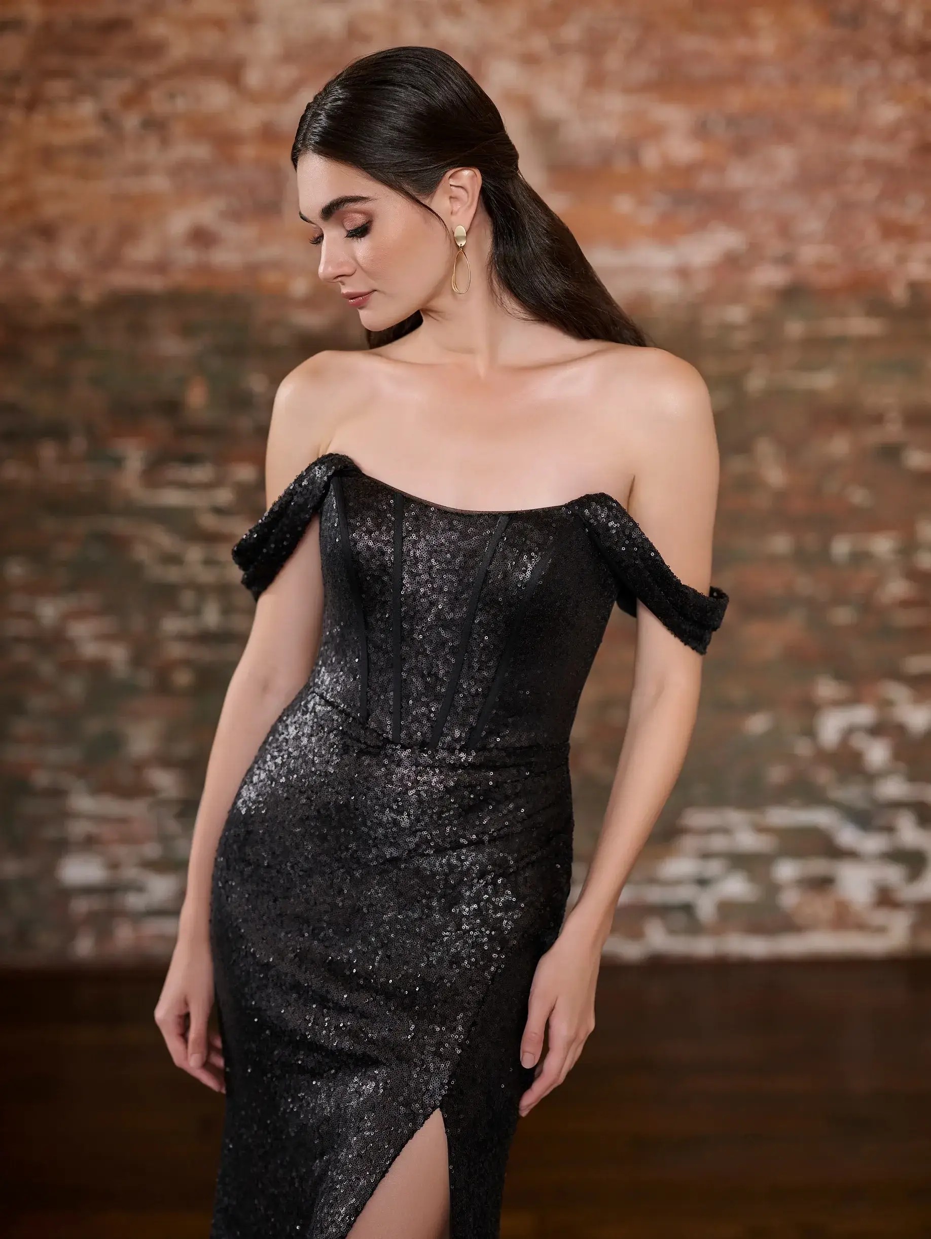 Model is wearing a sequin bridesmaid dress with an off the shoulder neckline and corset style bodice 