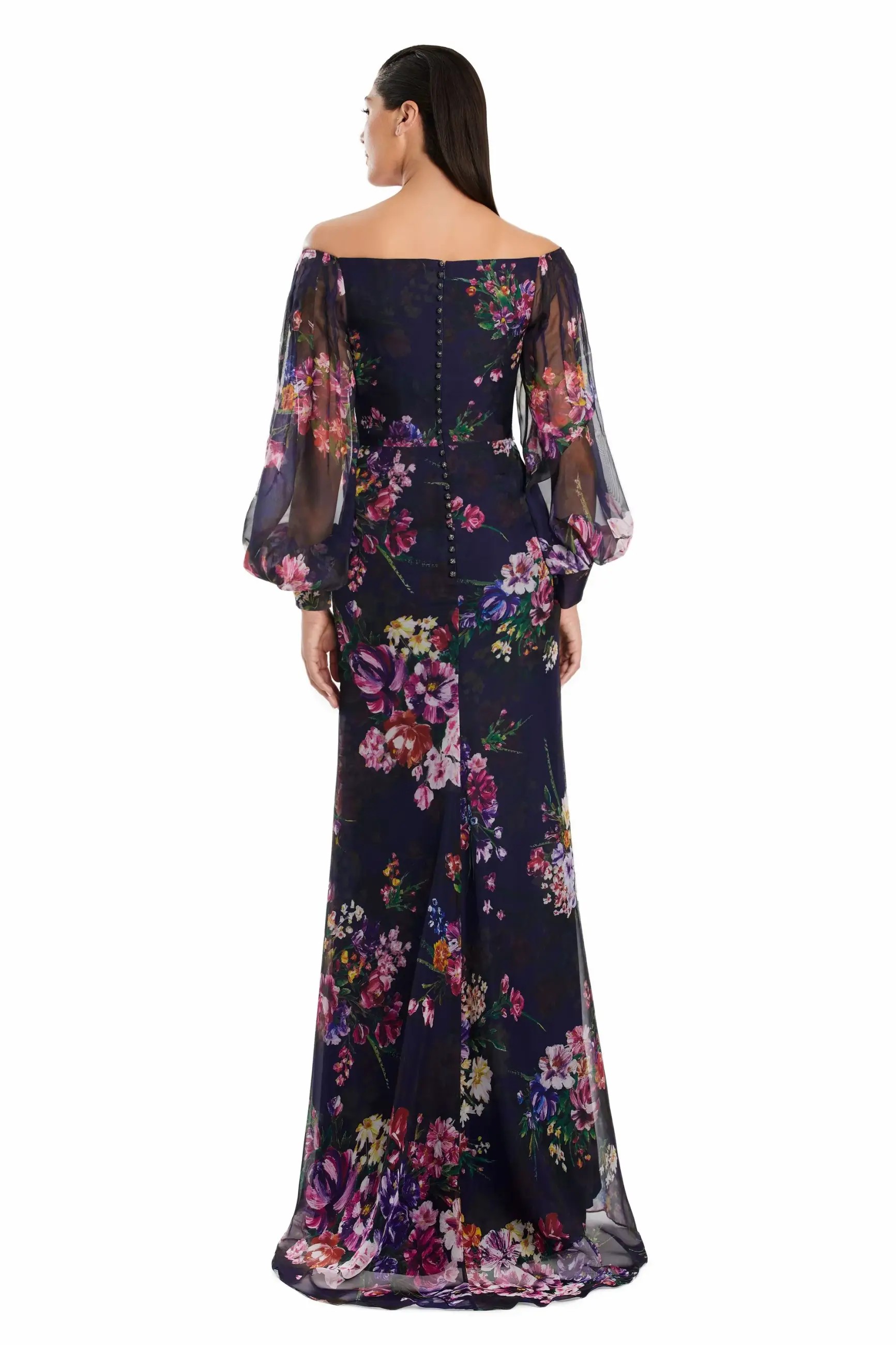 Model is wearing a floral printed chiffon off the shoulder gown with sheer bishop sleeves