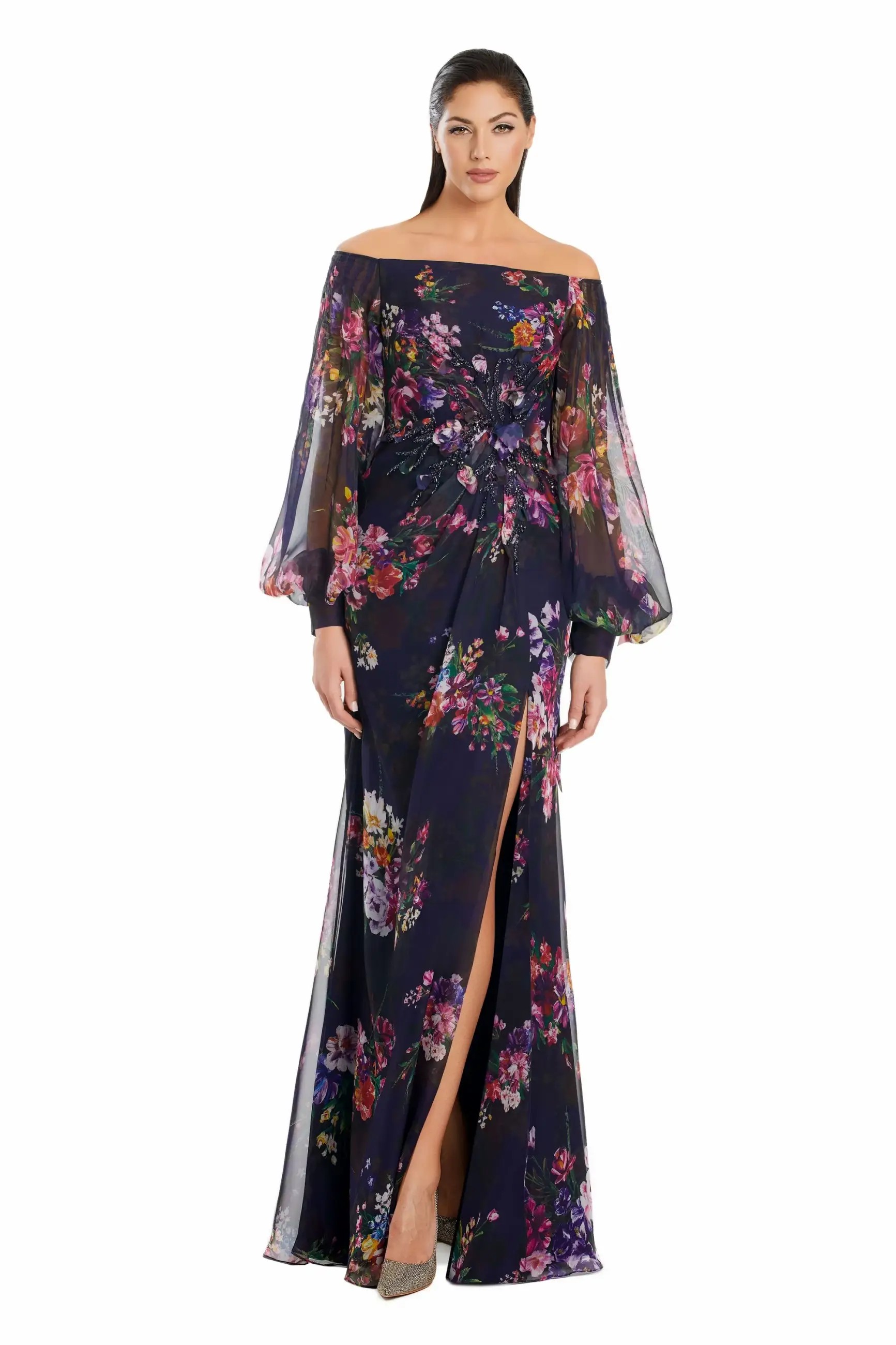 Model is wearing a floral printed chiffon off the shoulder gown with sheer bishop sleeves