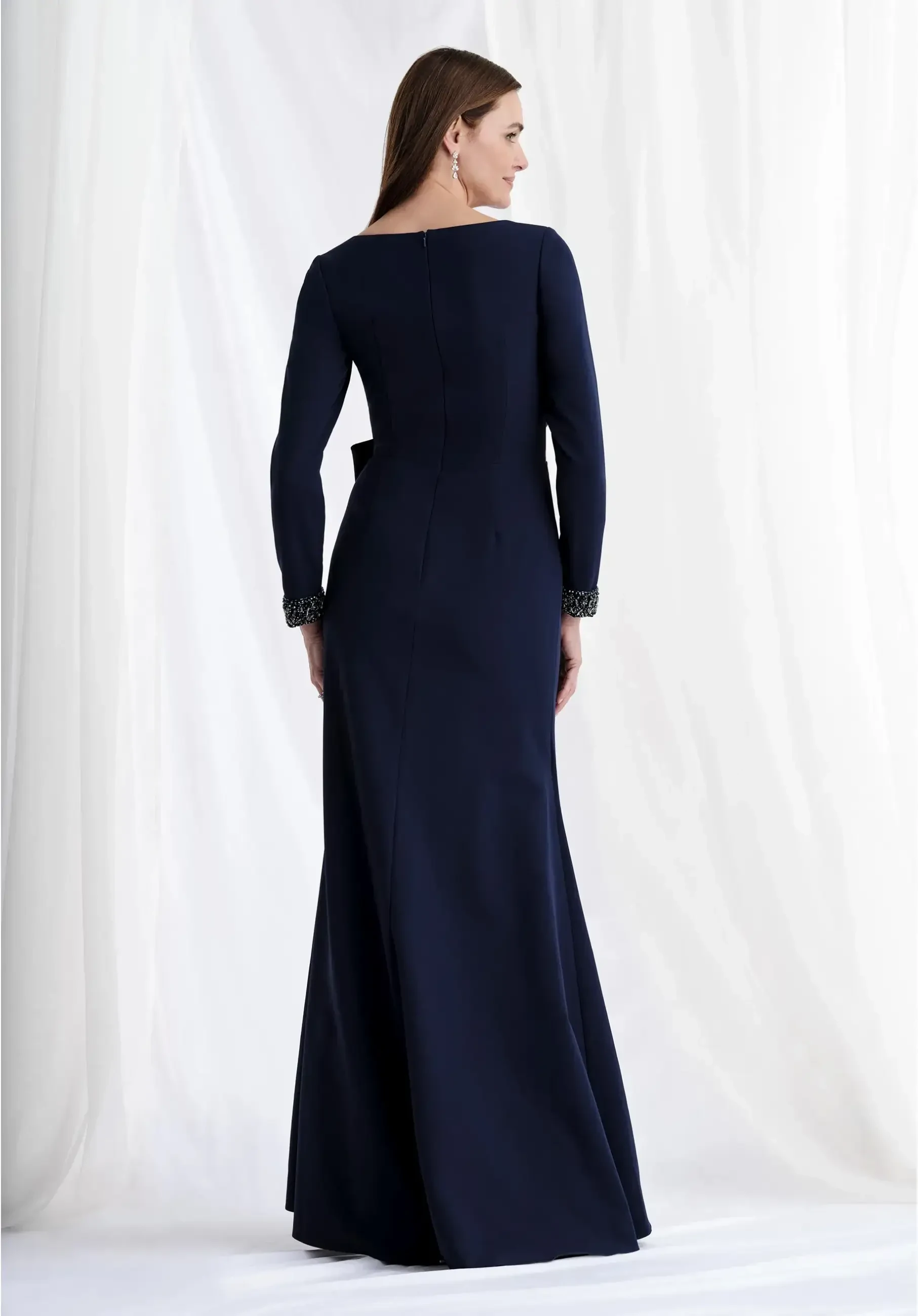 Fit and flare scuba knit gown with a deep V-neckline, beaded cuffs, and a bow detail at the waist.