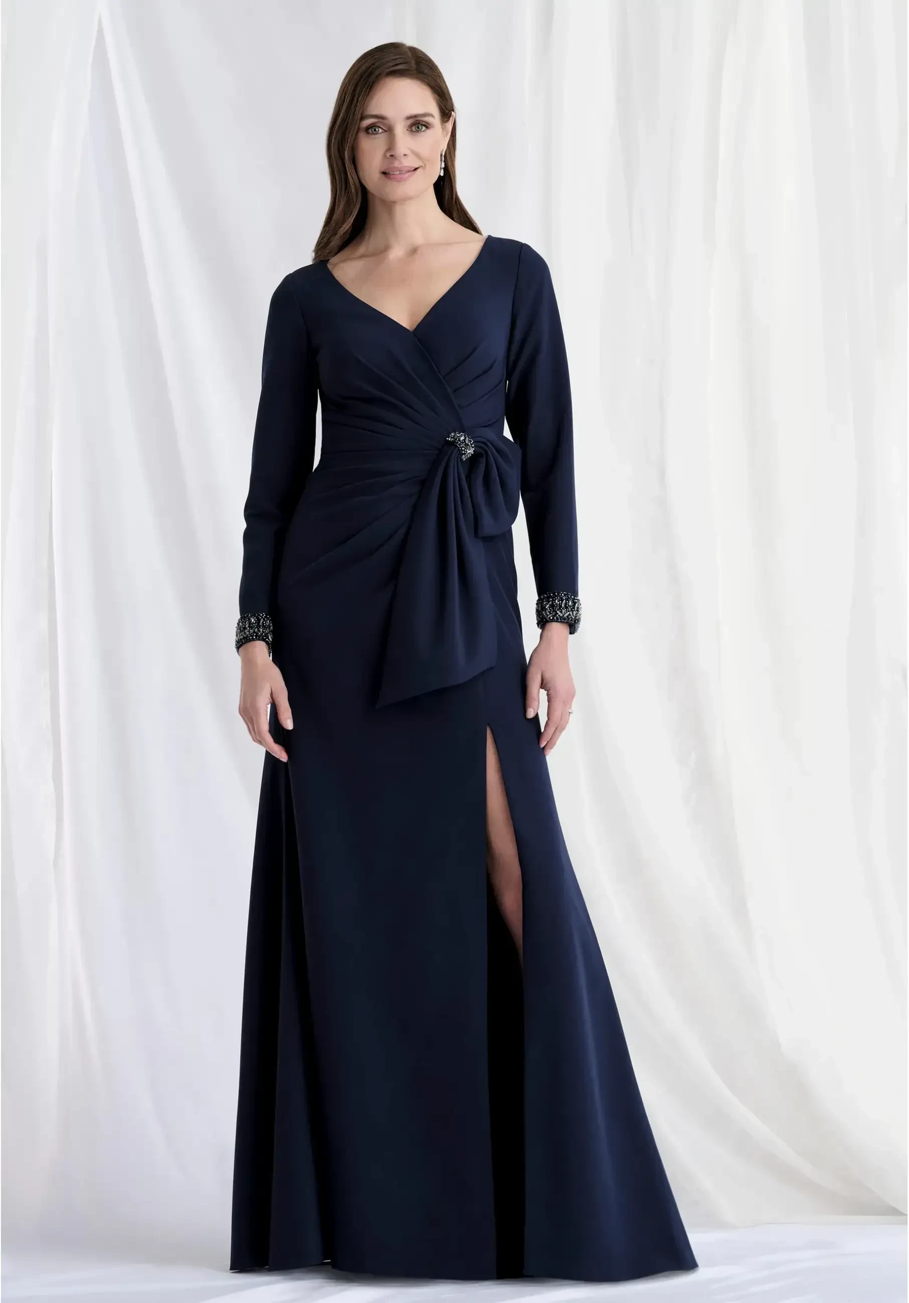 Fit and flare scuba knit gown with a deep V-neckline, beaded cuffs, and a bow detail at the waist.